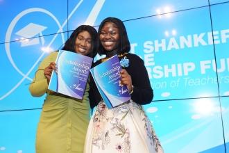 Two women hold up their awards on stage