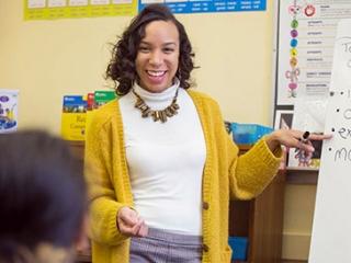 Single teacher standing at whiteboard, smiling