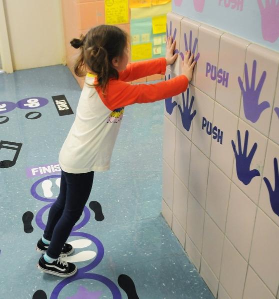 special ed and IEPs child presses against a school building wall with handprints and the word 'push'